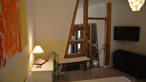 Une pièce avec une échelle en bois, un téléviseur à écran plat, une lampe et un tableau accroché au mur.