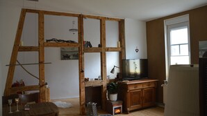 Une pièce avec une cloison en bois, un téléviseur, un radiateur et une fenêtre.