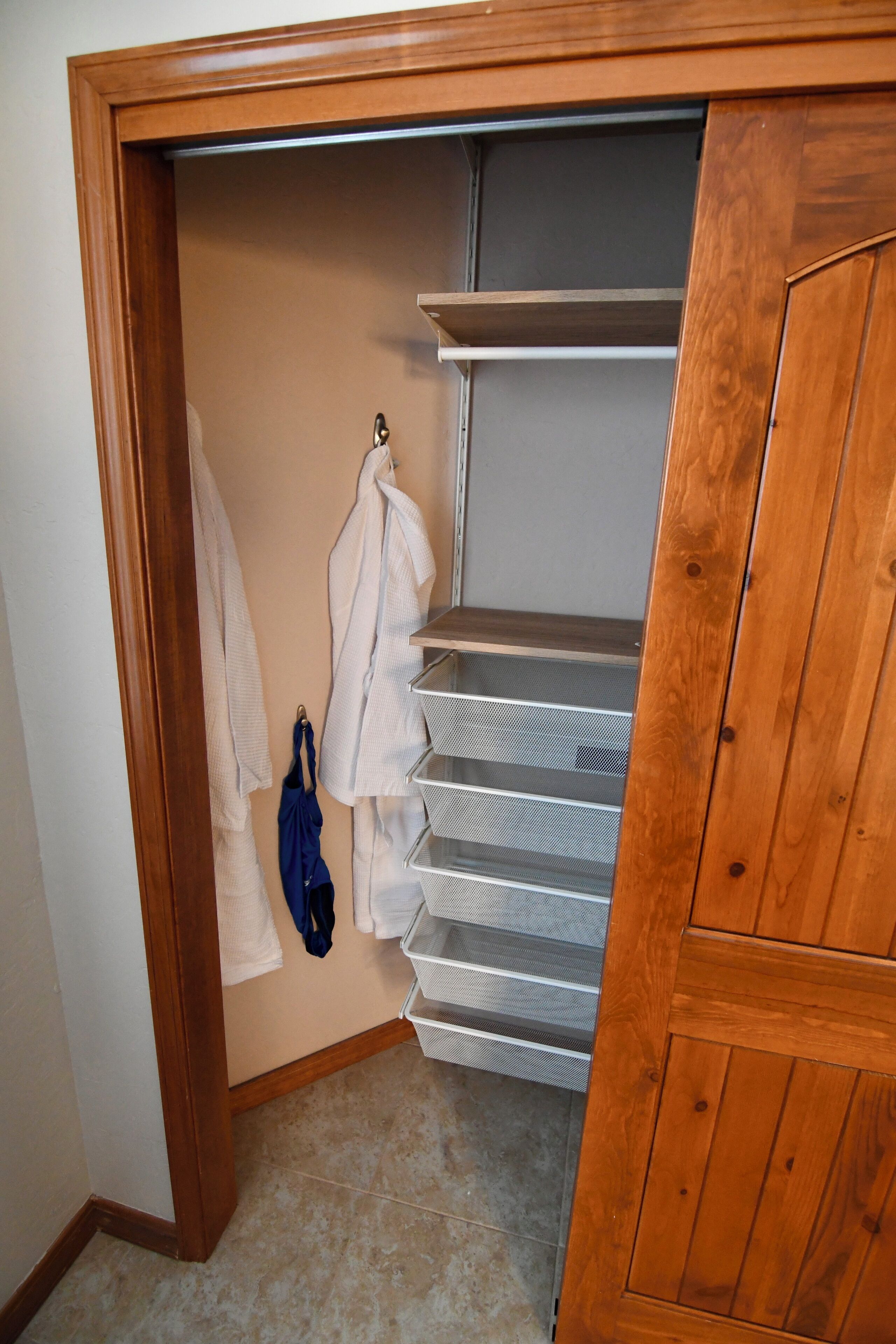 A closet with wooden doors, shelves, and hanging storage.