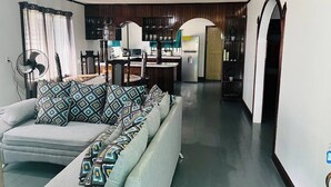 A modern living room with a sofa, a dining area, and a kitchen.