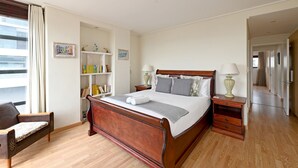 Un dormitorio ordenado con cama de madera, mesitas de noche, una estantería y una silla.