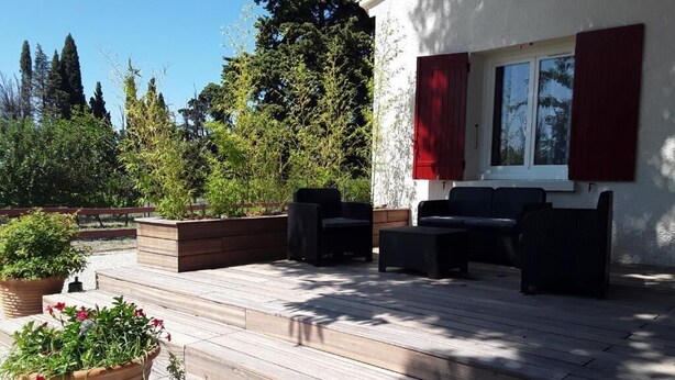 A wooden deck with outdoor furniture, a window with red shutters, and potted plants. - Family Villa LA BONBONNE EN PROVENCE 8-10 pers 5 bedrooms, swimming pool, quiet, Vaucluse (Travaillan)