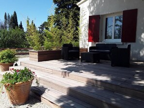 A wooden deck with outdoor furniture, a window with red shutters, and potted plants. - Family Villa LA BONBONNE EN PROVENCE 8-10 pers 5 bedrooms, swimming pool, quiet, Vaucluse (Travaillan)