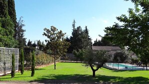 A fenced yard with a swimming pool, trees, and a building with a tiled roof. - Family Villa LA BONBONNE EN PROVENCE 8-10 pers 5 bedrooms, swimming pool, quiet, Vaucluse (Travaillan)