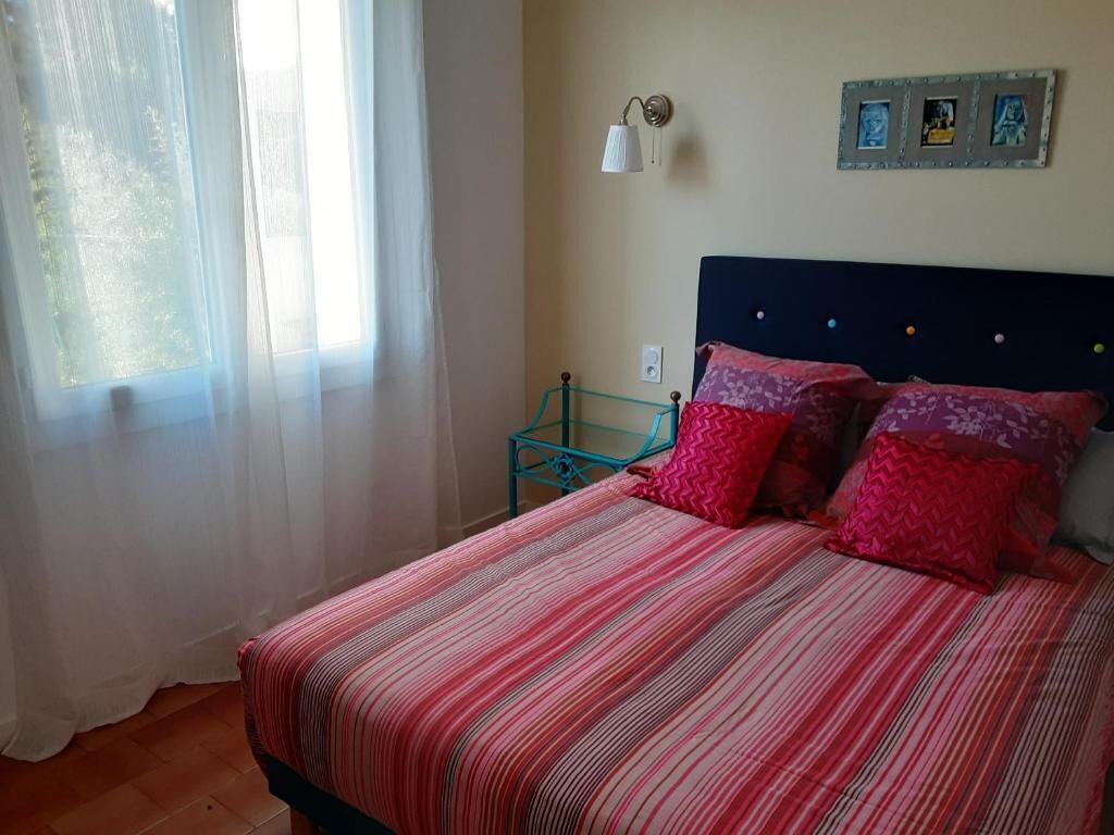 Une chambre à coucher avec un lit, des rideaux, une table de chevet et des lampes fixées au mur.