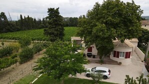 A house with a garden, a car, and a vineyard in the background. - Family Villa LA BONBONNE EN PROVENCE 8-10 pers 5 bedrooms, swimming pool, quiet, Vaucluse (Travaillan)