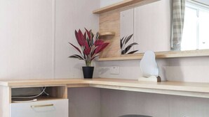 Un bureau d’angle agrémenté d’une plante en pot, d’une lampe blanche et d’un miroir.