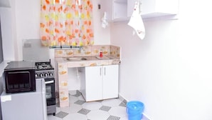 Une cuisine compacte équipée d’une cuisinière à gaz, d’un four encastré, d’un évier et d’un petit plan de travail.