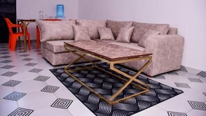 Un salon moderne avec un canapé beige, une table basse en bois aux pieds dorés et un tapis à motifs.