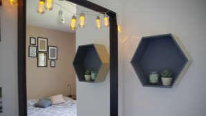 Een slaapkamer met een bed, een spiegel, zeshoekige planken met planten en lichtslingers.