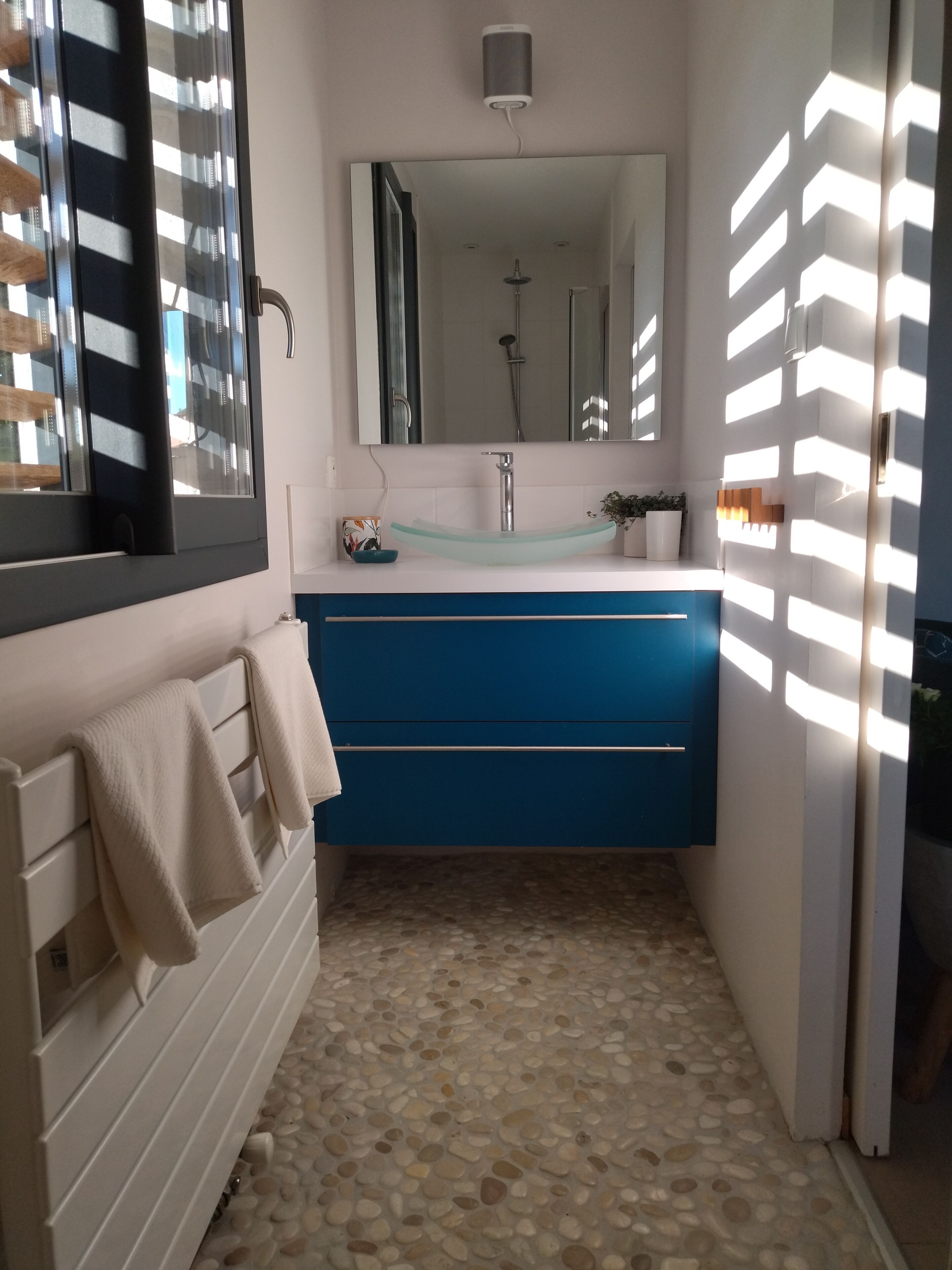 A bathroom with a blue vanity, a white sink, and a mirror above it.