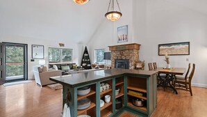 A spacious living area with a large island, a fireplace, and a dining table. - Colt Mountain Lodge. (Bozeman)