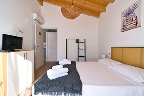 Une chambre d’hôtel avec un lit, une télévision, une armoire, un panier suspendu et un tableau au mur.