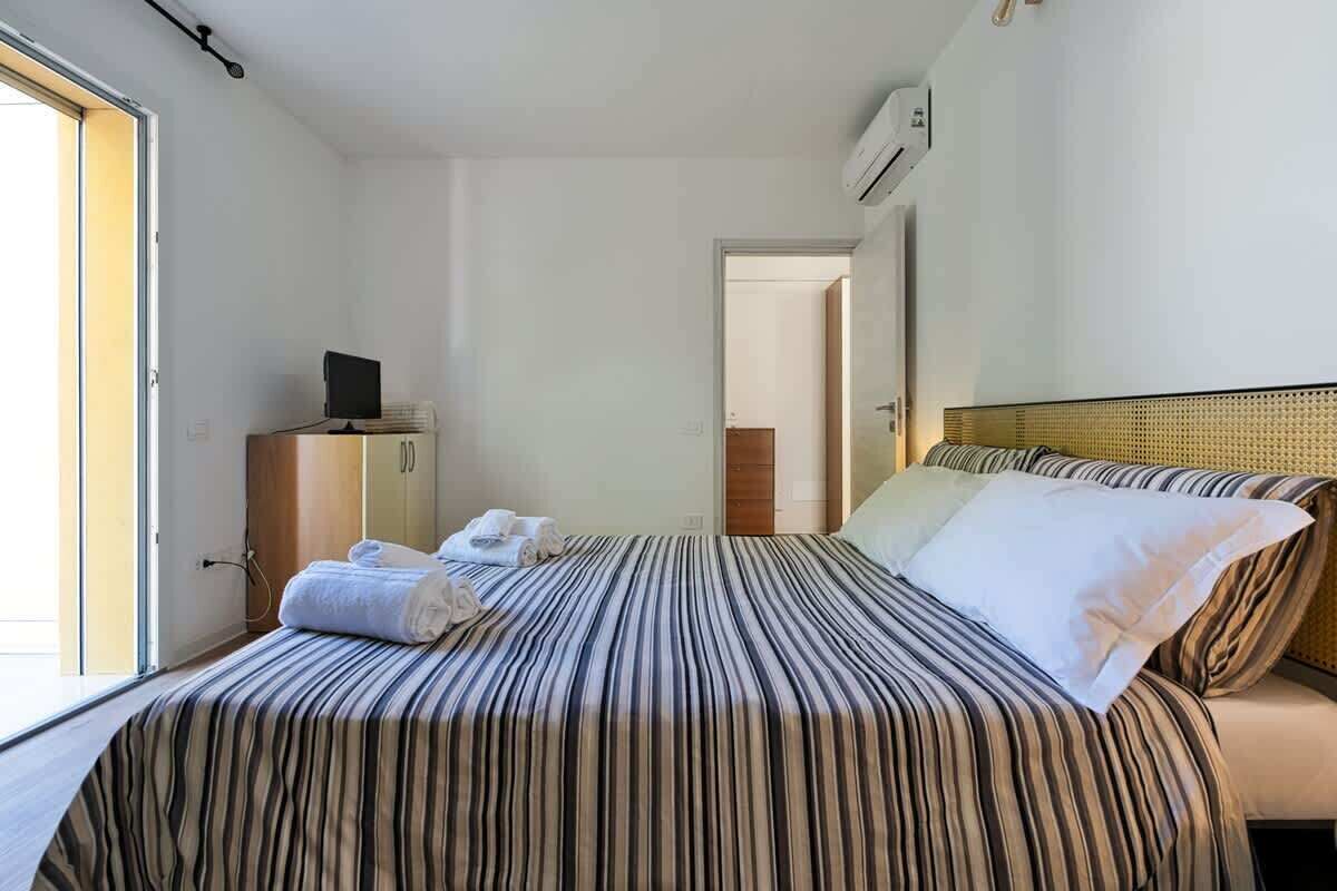 Una habitación de hotel con una cama, un escritorio con computadora y una ventana.