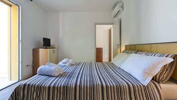 Una habitación de hotel con una cama, un escritorio con computadora y una ventana.