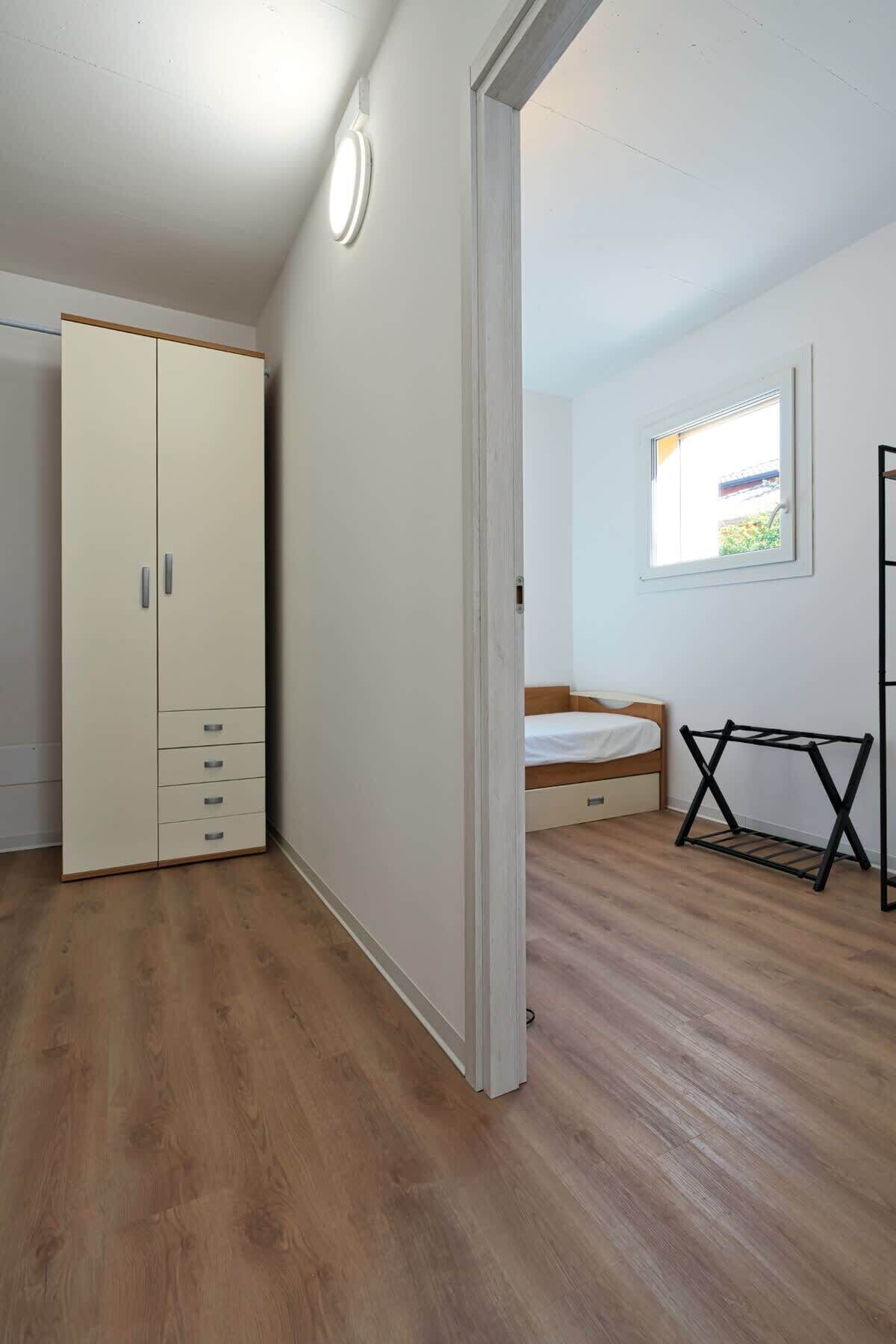 Ein Zimmer mit Kleiderschrank, Bett, Fenster und Wäscheständer.