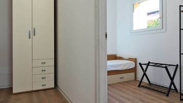Ein Zimmer mit Kleiderschrank, Bett, Fenster und Wäscheständer.