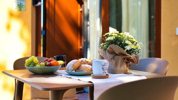 Una mesa de desayuno con un tazón de fruta, croissants y una taza de café.
