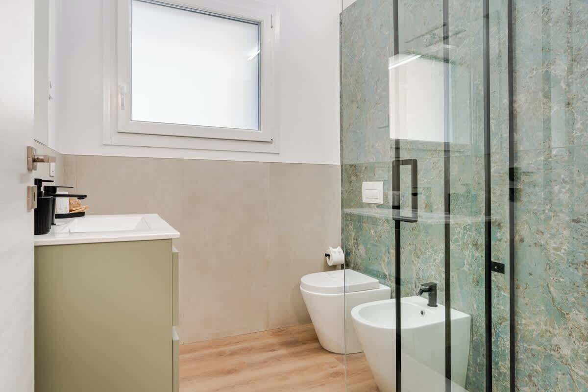 A modern bathroom with a glass shower enclosure, a toilet, and a sink.