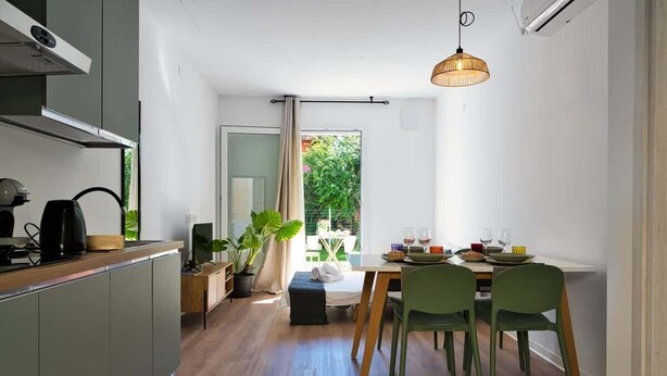A modern kitchen with a dining area, wooden flooring, and a view of greenery outside. - Garden Terrace Apartment w/ A/C & Parking (San Stino di Livenza)