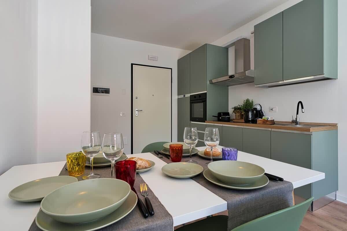 A modern kitchen with a dining table set for four, including plates, glasses, and cutlery.