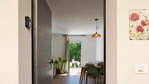 A narrow hallway leading to a dining area with a table and chairs, a hanging light fixture, and a door with a handle. - Garden Terrace Apartment w/ A/C & Parking (San Stino di Livenza)