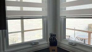 Una cocina con dos ventanas, un utensilio de madera y vistas a una terraza.