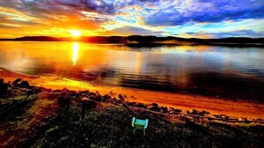 Un atardecer sobre un lago tranquilo con una silla en primer plano.