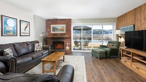 A living room with a fireplace, leather sofa, green armchair, and a TV.