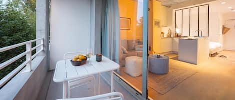 A modern apartment with a balcony, a dining area, and a living space with a sofa and a coffee table.