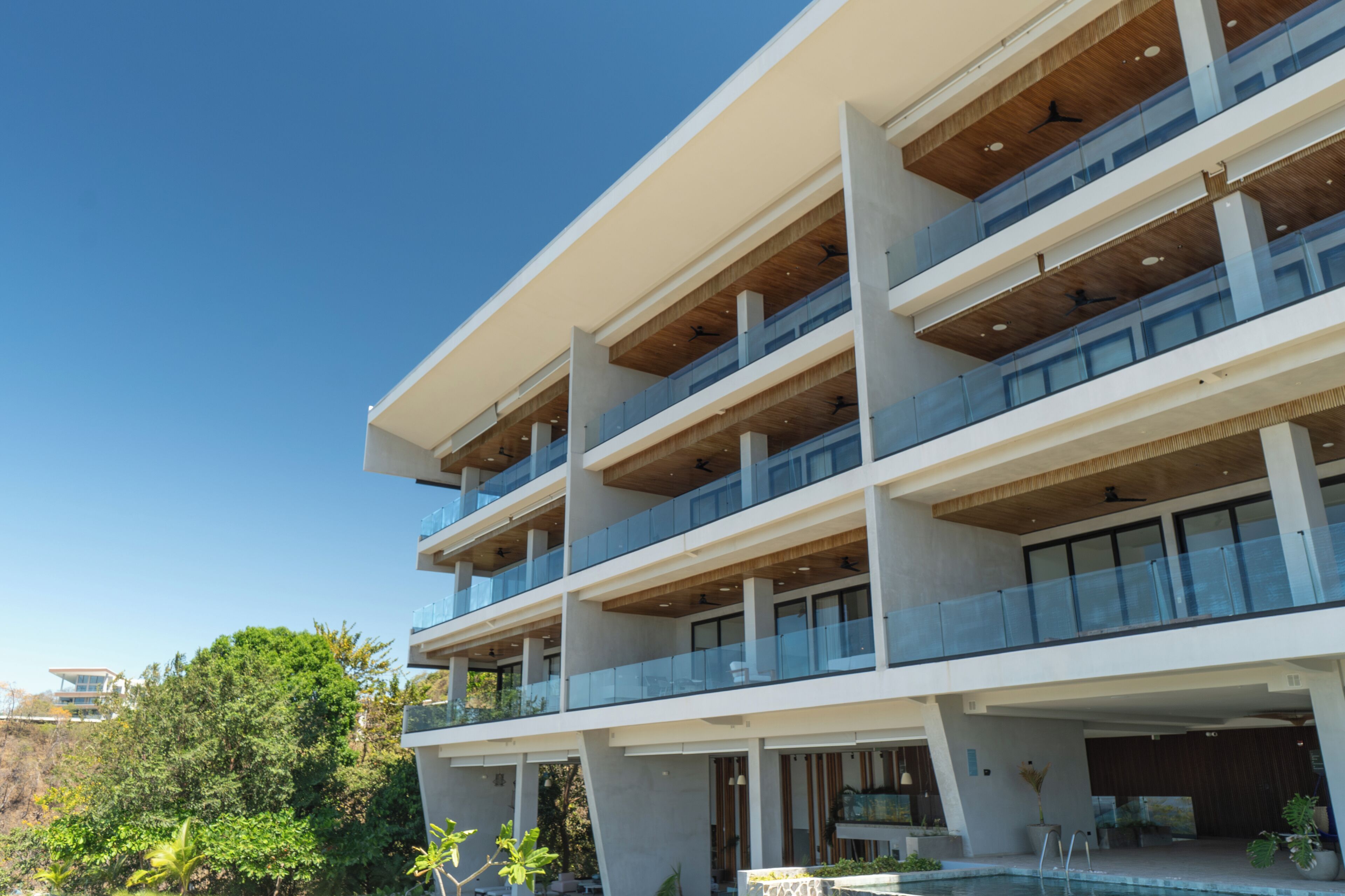 Un edifici modern d'àmbit elevat, amb balcons, grans finestres i zona de piscina.