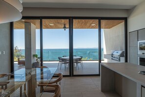 Een moderne keuken met een grote schuifglazen deur naar een balkon met uitzicht op zee.