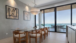 Un espace repas moderne avec une table en verre, des chaises en bois et des œuvres d’art accrochées au mur.