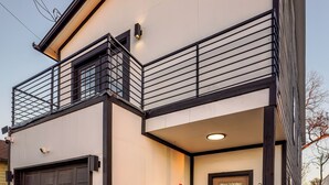 Ein modernes, zweigeschossiges Haus mit Garage, Eingangstür und Balkon.
