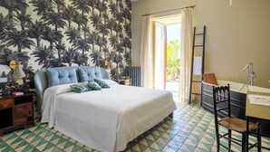 Een slaapkamer met een bed, een stoel, een bureau, een raam met gordijnen en een deur naar buiten.