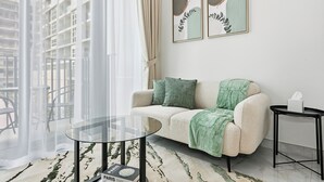 Ein modernes Wohnzimmer mit einer Couch, einem Glastisch und einem kleinen Beistelltisch.