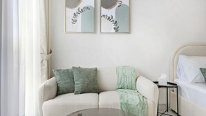 Ein modernes Schlafzimmer mit einer Couch, einem Bett und zwei gerahmten Kunstwerken an der Wand.