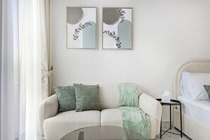 Een moderne slaapkamer met een bank, een bed en twee ingelijste kunstwerken aan de muur.