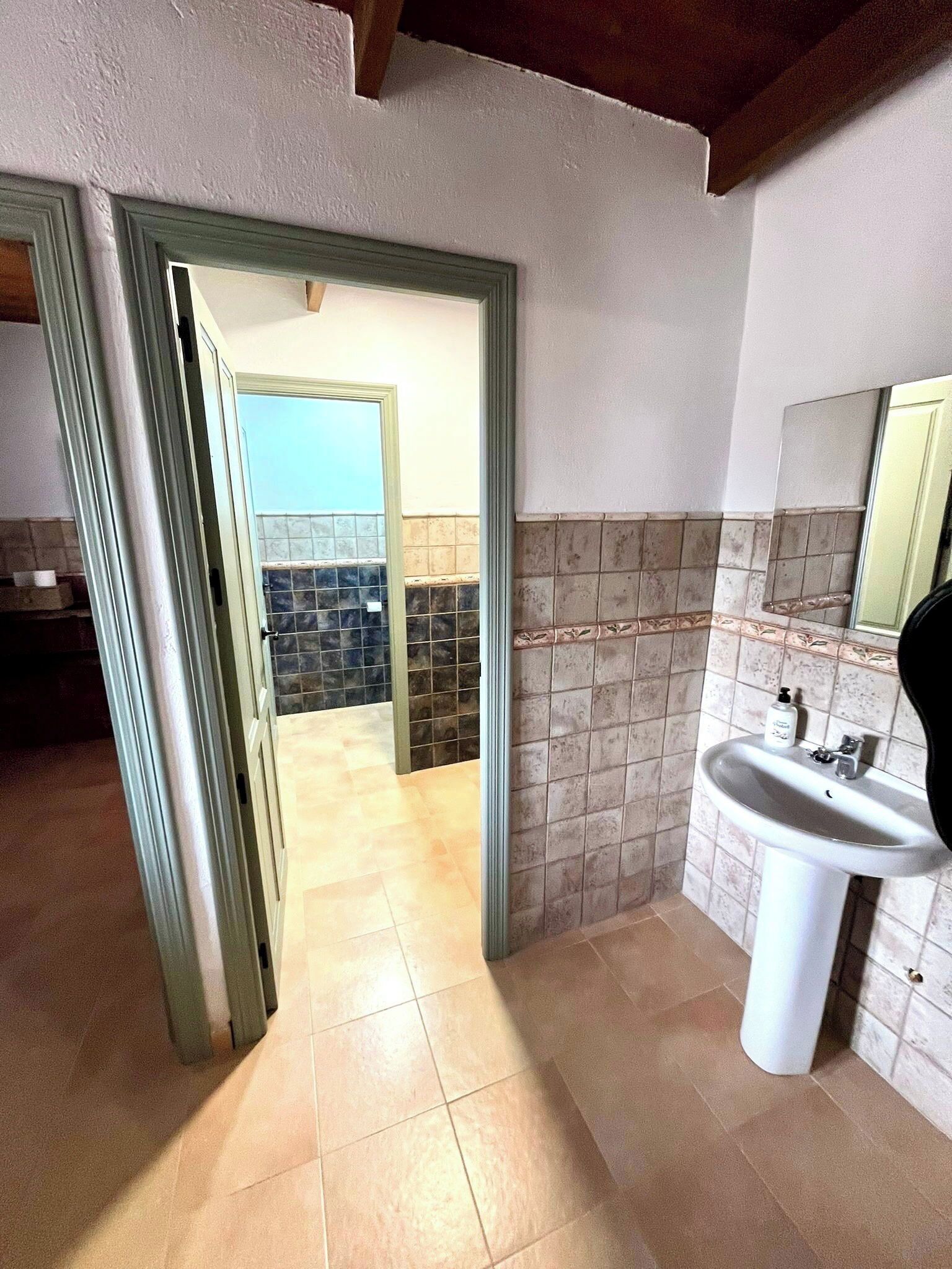 Un baño con lavabo, espejo y paredes de azulejos.