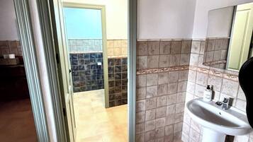 Un baño con lavabo, espejo y paredes de azulejos.