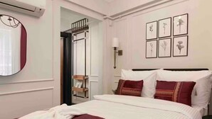 Een hotelkamer met een bed, een spiegel, een wandairconditioner, een deur en lijstwerken met afbeeldingen van planten.