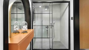 Ein modernes Badezimmer mit einer gläsernen Duschkabine, einem Holzwaschtisch mit Spiegel und einer Holztür.