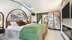 Ein modernes Schlafzimmer mit einem großen Bett, einem Fernseher und Kunstwerken an den Wänden.