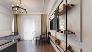 A modern hotel room with a wooden floor, a sofa, a dining table with chairs, a TV mounted on the wall, and a decorative shelf with a neon sign. - Daphne Pera; Jasmin Apart, City Center (Beyoglu)
