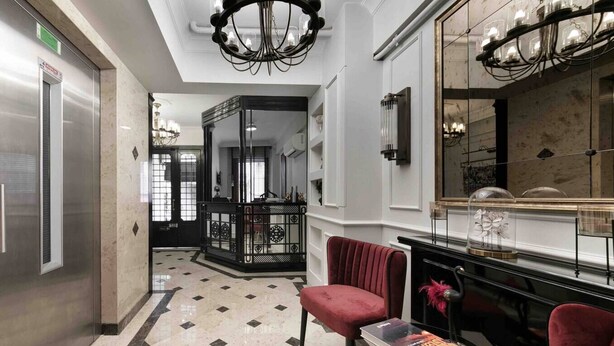 A hotel lobby with a check-in desk, a red velvet chair, a chandelier, and a large mirror. - Daphne Pera; Jasmin Apart, City Center (Beyoglu)
