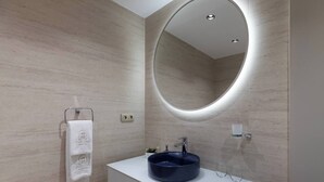 A modern bathroom with a round mirror, a white vanity, and a blue sink. - The One Taksim 105 Room, Comfort & Privacy (Beyoglu)