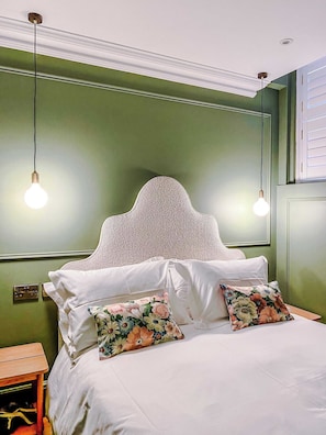 A bed with white linens and floral pillows, a wooden nightstand, and a green wall with a decorative headboard. - Railway House (Free Gated Parking) - Platform 4 (York)