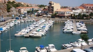 A marina with numerous boats docked, surrounded by buildings and a road with vehicles. - Front-line studio cabin (Fleury)