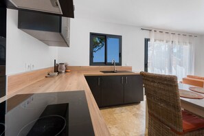 A modern kitchen with a built-in stove, a sink, and a window with a view of the outdoors. - La Volière du Pesquier – Holiday Home in Provençal Pine Forest with Pool and Garden (Pélissanne)