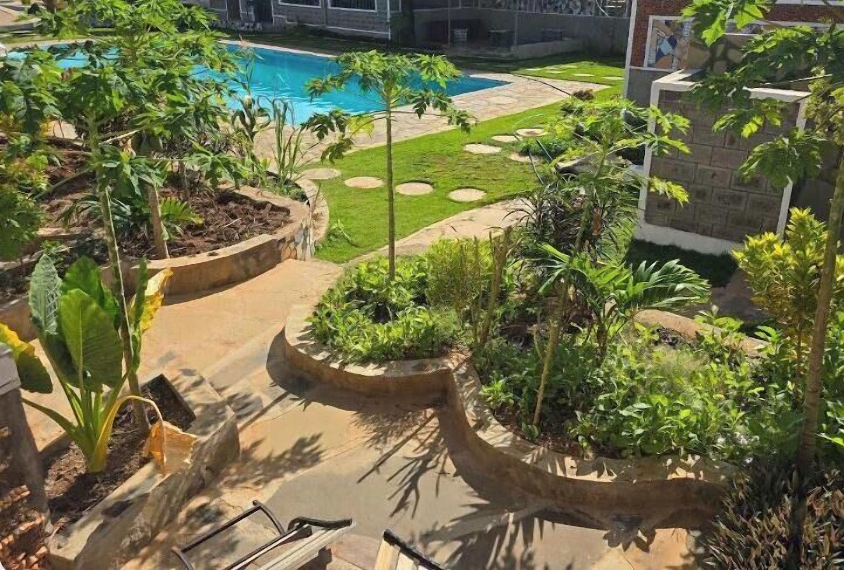 A landscaped outdoor area with a pool, garden beds, and a stone pathway.